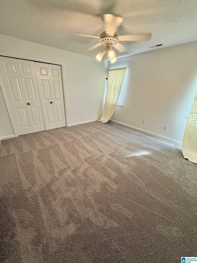 unfurnished bedroom featuring carpet flooring, a textured ceiling, a closet, and ceiling fan