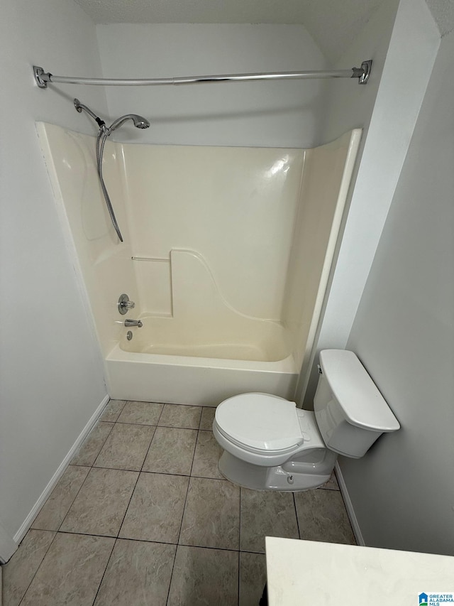 bathroom featuring tile patterned flooring, toilet, and shower / washtub combination