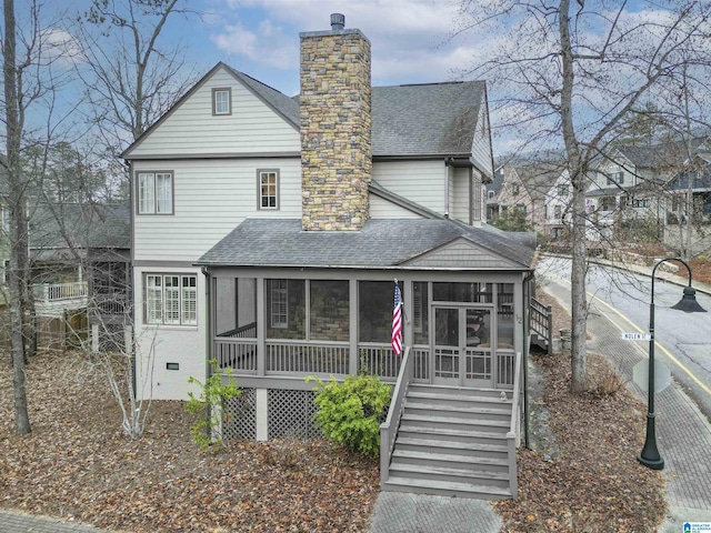 view of front of house featuring stairs, roof with shingles, a chimney, and a sunroom