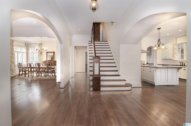 interior space featuring an inviting chandelier, ornamental molding, and dark wood-type flooring