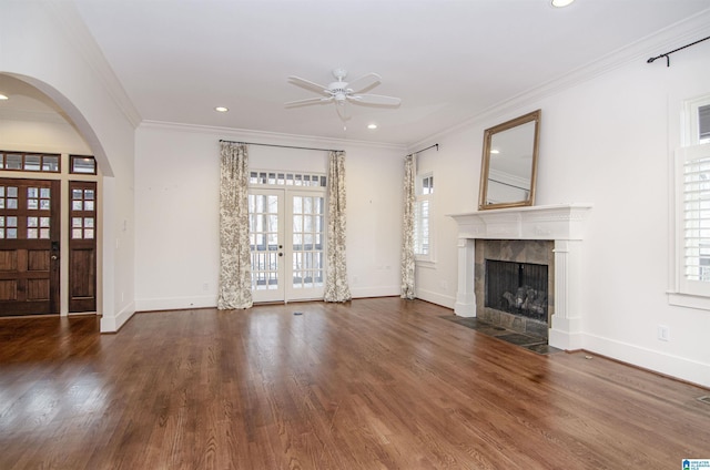 unfurnished living room with dark hardwood / wood-style flooring, a tiled fireplace, ceiling fan, crown molding, and french doors