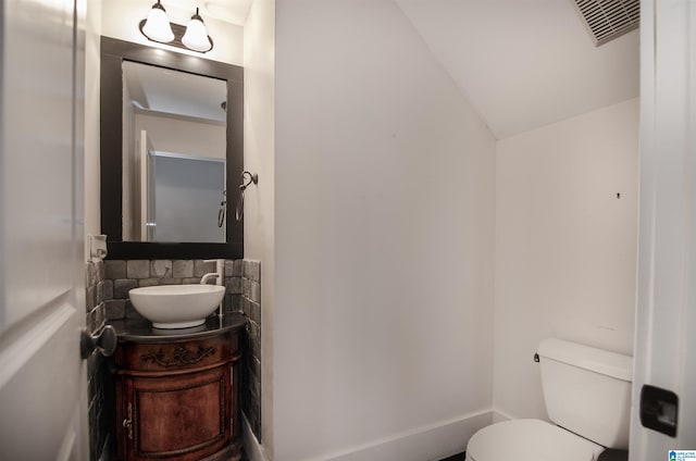 bathroom with vanity, lofted ceiling, and toilet