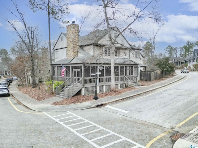 exterior space featuring stairway, a sunroom, and a chimney