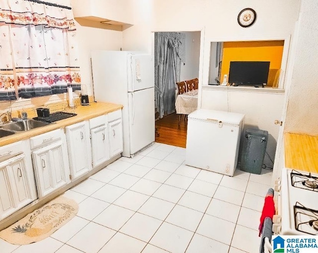 kitchen featuring refrigerator, white refrigerator, range with gas cooktop, and light tile patterned flooring