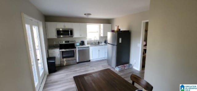 kitchen featuring sink, white cabinets, stainless steel appliances, and light hardwood / wood-style floors