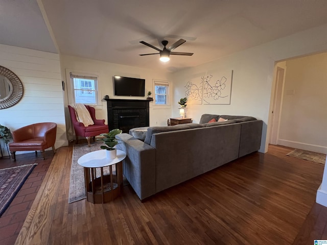 living room with dark hardwood / wood-style floors, a brick fireplace, and ceiling fan