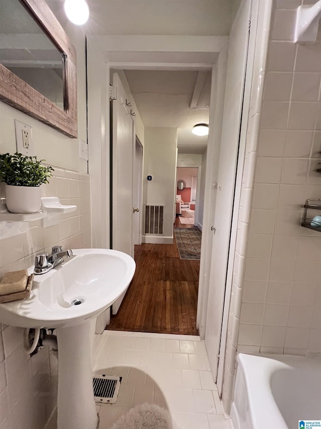 bathroom with tile patterned flooring, a tub to relax in, and tile walls