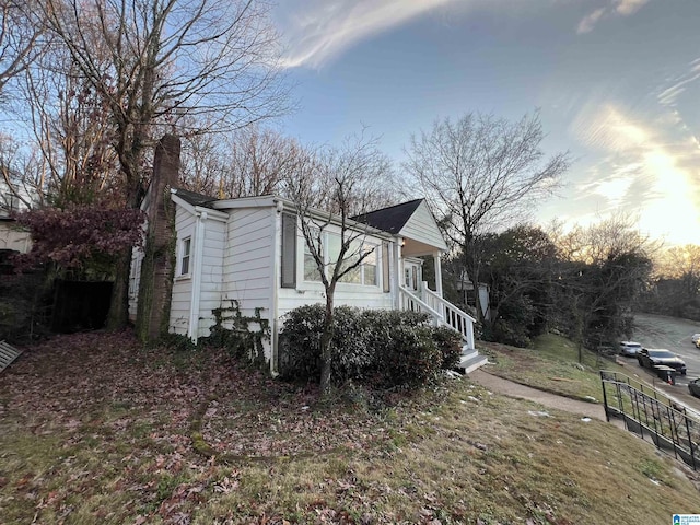 property exterior at dusk featuring a lawn