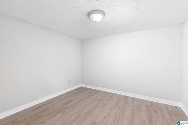 empty room featuring a textured ceiling and light hardwood / wood-style flooring