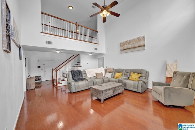 living room featuring wood-type flooring, a towering ceiling, and ceiling fan