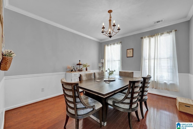 dining area with a notable chandelier, wood-type flooring, and crown molding