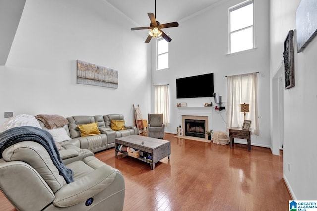 living room with hardwood / wood-style floors, ceiling fan, and a towering ceiling