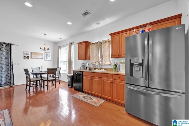 kitchen with light stone countertops, dishwasher, an inviting chandelier, stainless steel refrigerator with ice dispenser, and decorative light fixtures