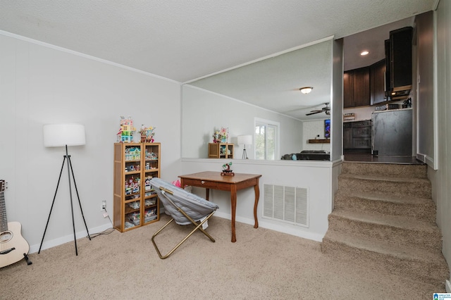 interior space with ceiling fan, ornamental molding, light carpet, and a textured ceiling