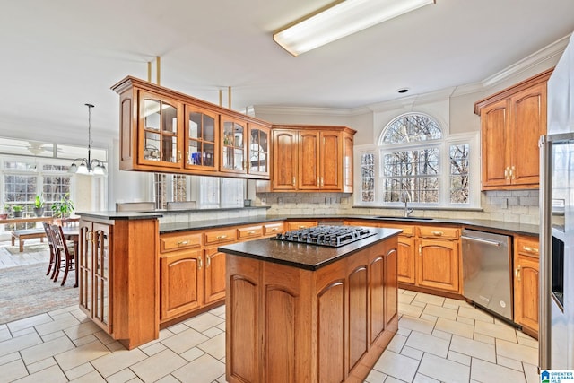 kitchen with sink, a center island, stainless steel appliances, pendant lighting, and ornamental molding