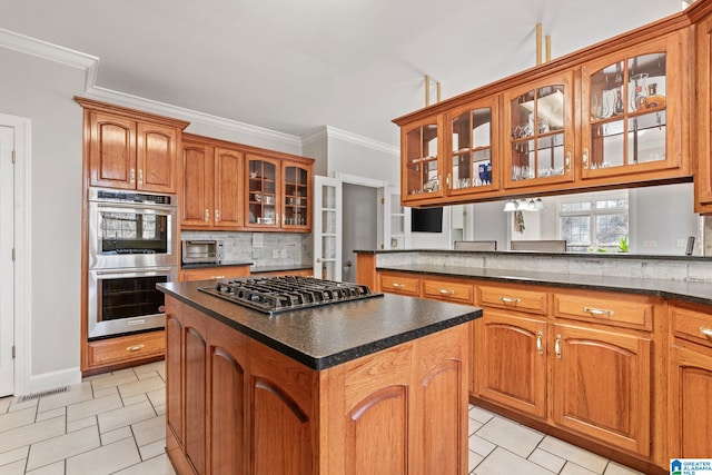 kitchen featuring decorative backsplash, ornamental molding, stainless steel appliances, light tile patterned floors, and a center island