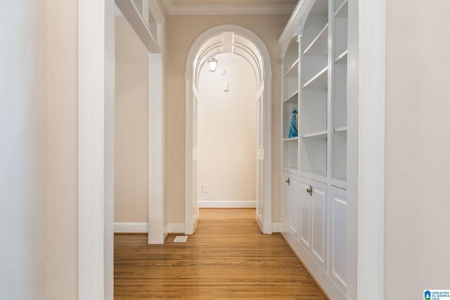 hall with light hardwood / wood-style floors and crown molding