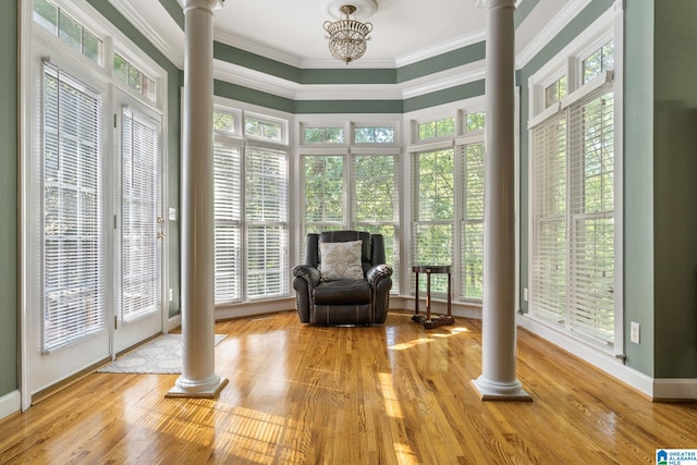 sitting room featuring light wood-type flooring, an inviting chandelier, and ornate columns