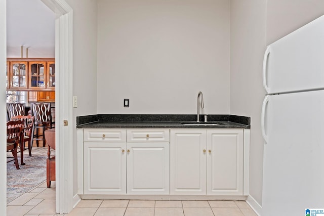 kitchen featuring white cabinetry, sink, light tile patterned floors, and white refrigerator