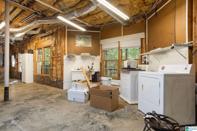 basement featuring washing machine and clothes dryer, electric panel, and a wealth of natural light