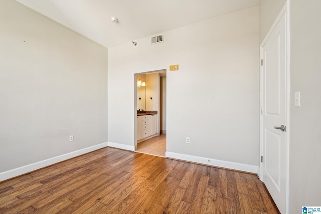 unfurnished bedroom featuring light wood-type flooring and connected bathroom