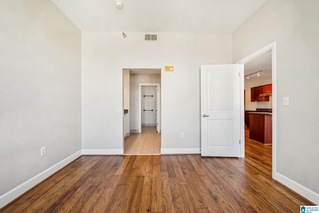 unfurnished bedroom with track lighting and hardwood / wood-style floors