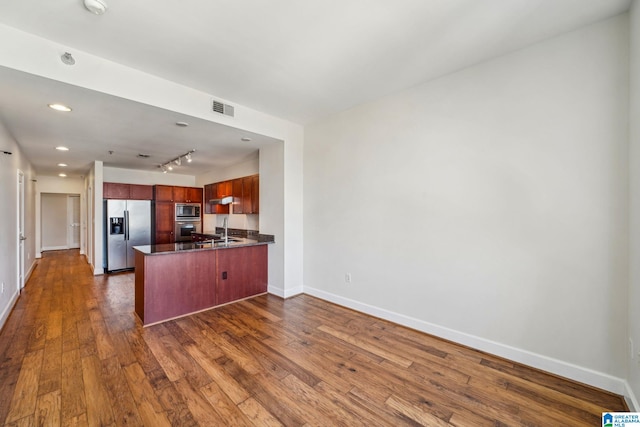 kitchen with kitchen peninsula, dark hardwood / wood-style floors, stainless steel appliances, track lighting, and sink