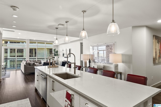 kitchen featuring sink, dark hardwood / wood-style floors, white cabinetry, hanging light fixtures, and an island with sink