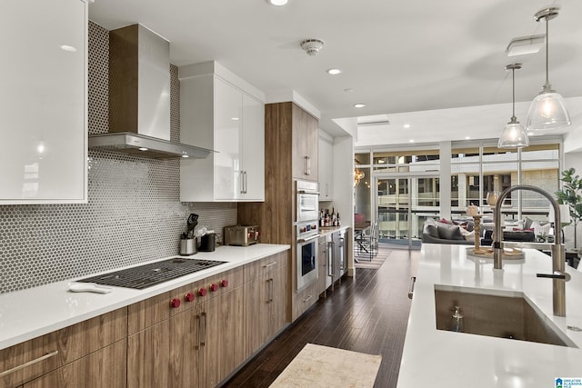 kitchen featuring sink, hanging light fixtures, wall chimney exhaust hood, stovetop, and dark hardwood / wood-style flooring