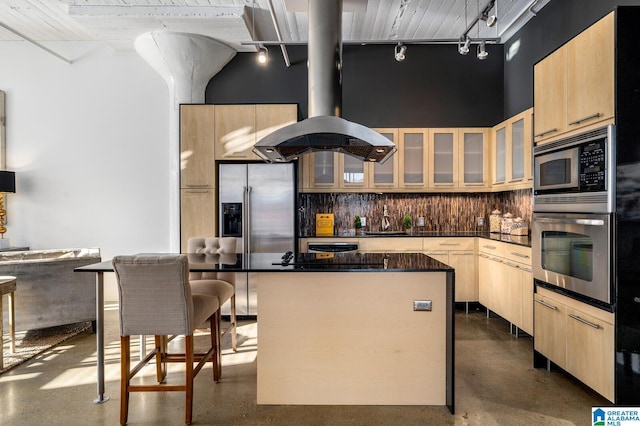 kitchen with a center island, light brown cabinetry, appliances with stainless steel finishes, and track lighting