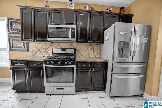 kitchen featuring appliances with stainless steel finishes, light tile patterned floors, dark brown cabinetry, and decorative backsplash