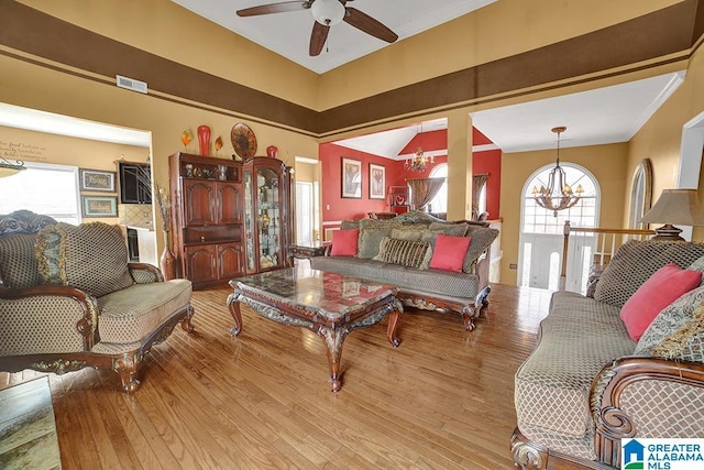 living room with crown molding, plenty of natural light, ceiling fan with notable chandelier, and light wood-type flooring