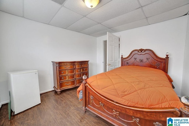 bedroom featuring a drop ceiling, dark hardwood / wood-style floors, and refrigerator