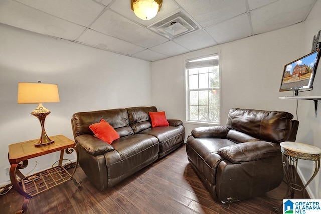 living room featuring a paneled ceiling and dark hardwood / wood-style flooring