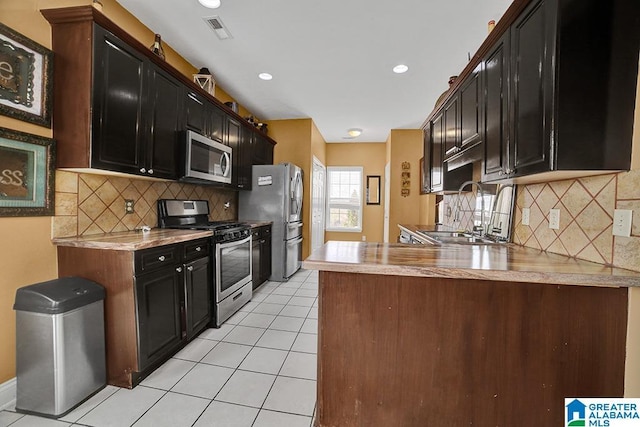 kitchen with sink, light tile patterned floors, stainless steel appliances, decorative backsplash, and kitchen peninsula