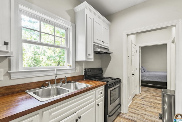 kitchen featuring white cabinets, butcher block counters, electric stove, and sink