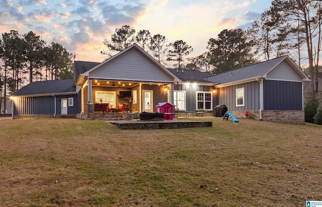 back house at dusk featuring a patio area and a yard