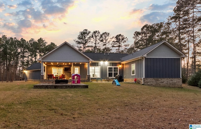 back house at dusk with a lawn