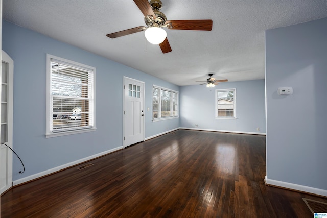 unfurnished living room with a textured ceiling, ceiling fan, a healthy amount of sunlight, and dark wood-type flooring