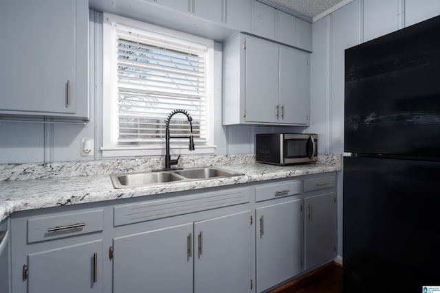 kitchen with white cabinets, black refrigerator, and sink