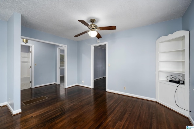 empty room featuring dark hardwood / wood-style flooring, ceiling fan, built in features, and a textured ceiling