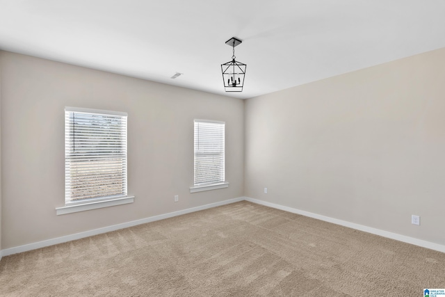 carpeted spare room with a chandelier and a healthy amount of sunlight