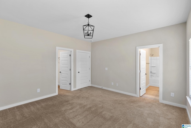 unfurnished bedroom with light colored carpet and connected bathroom