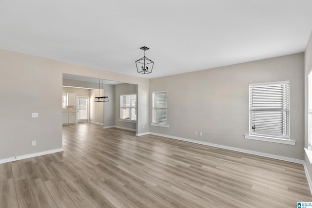 unfurnished living room featuring a chandelier and light hardwood / wood-style floors