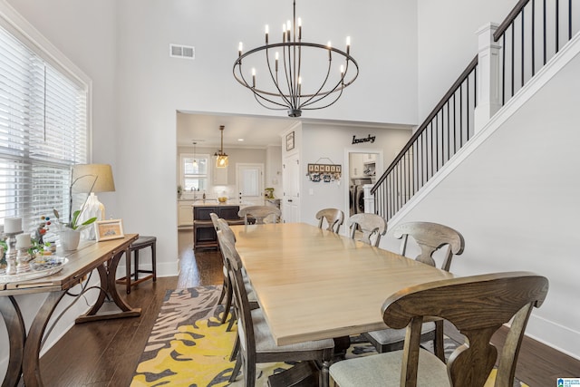 dining area featuring a high ceiling, ornamental molding, a notable chandelier, and dark hardwood / wood-style floors