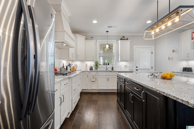 kitchen featuring white cabinets, stainless steel appliances, pendant lighting, and custom range hood