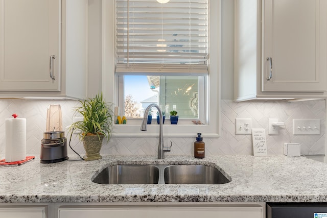 kitchen featuring light stone countertops, backsplash, and sink