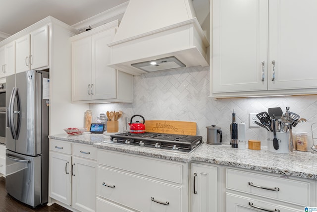 kitchen featuring white cabinets, premium range hood, appliances with stainless steel finishes, and backsplash