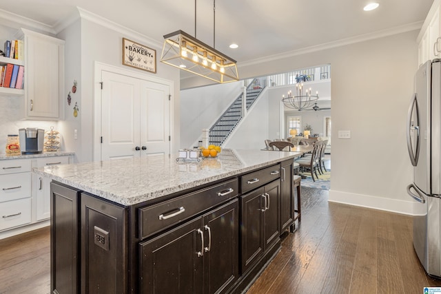 kitchen with decorative light fixtures, white cabinetry, stainless steel fridge, a kitchen island, and crown molding