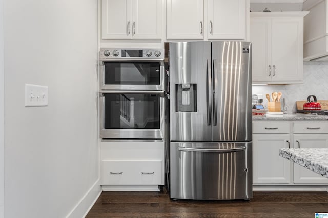 kitchen featuring appliances with stainless steel finishes, white cabinetry, backsplash, and light stone countertops